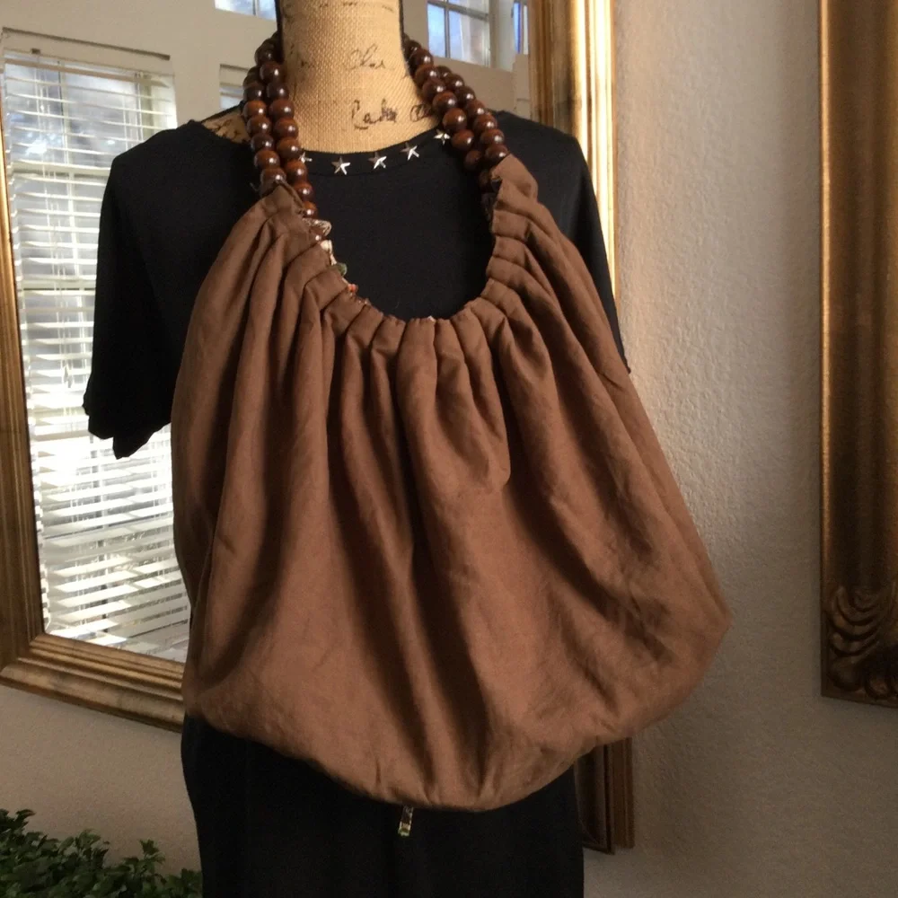 Reversible hobo tote with brown wood balls straps. Has a tie strap closu…